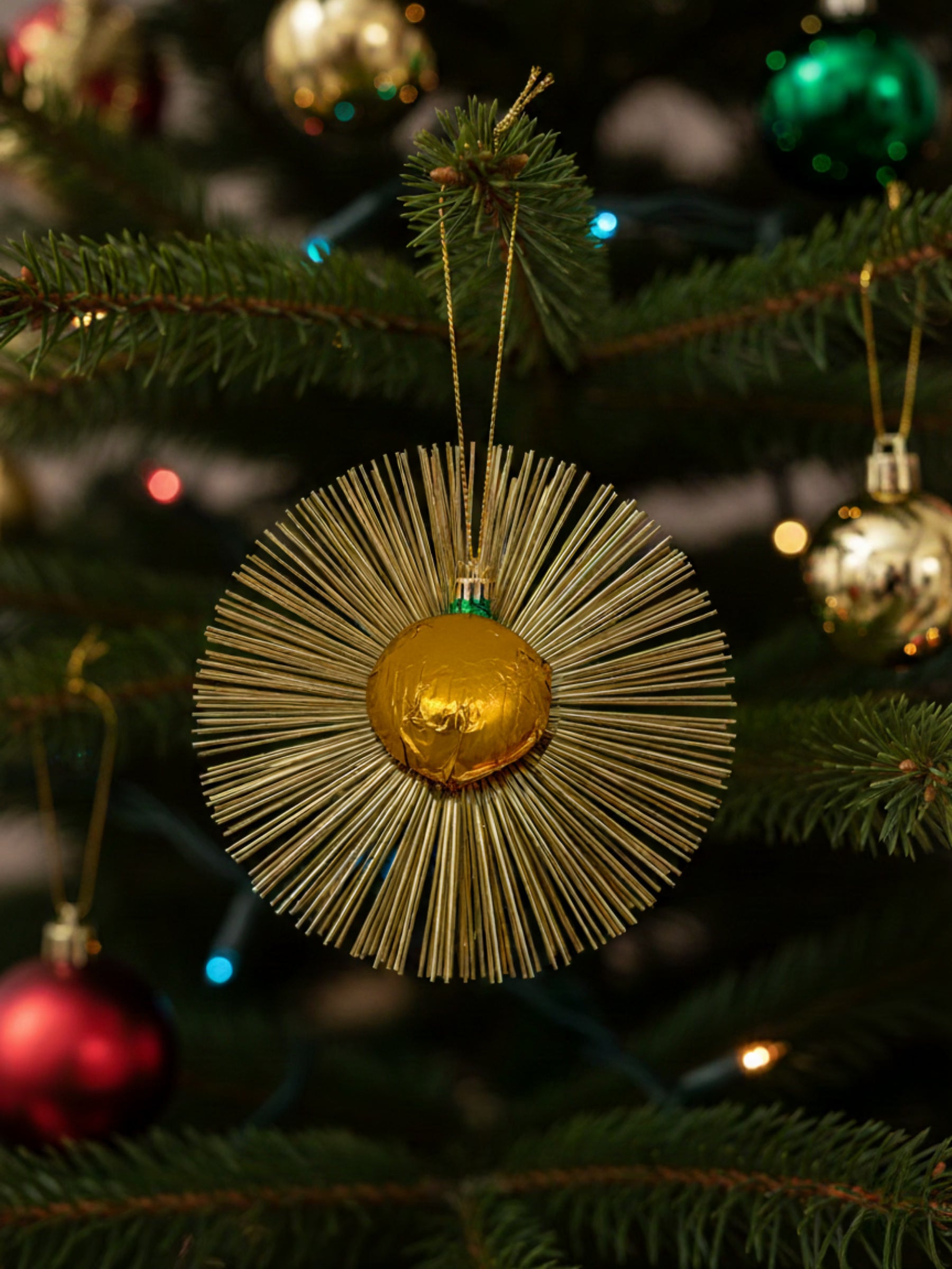 Flimmerstern in der Farbe gelb aus Vollmilchschokolade 10g mit goldenem Lametta und Aufhänger, essbarer Christbaumschmuck, erhältlich in der Dreyer Confiserie in Hameln.