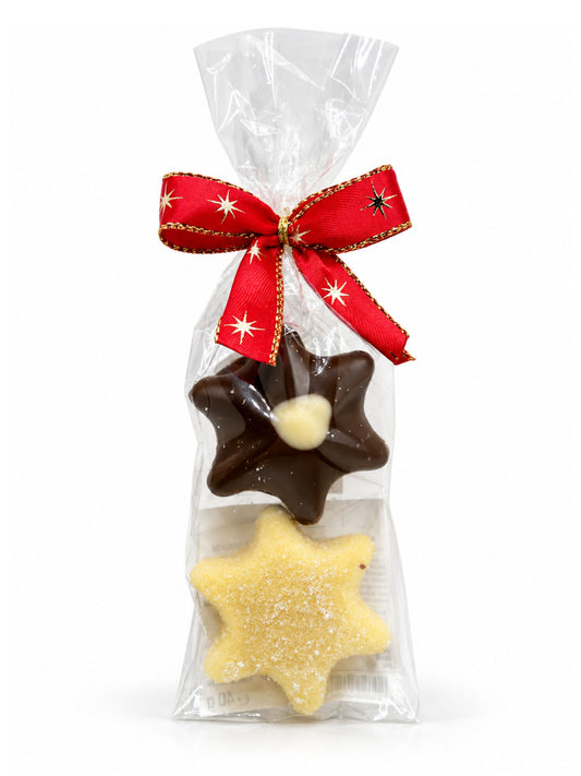 Maxi-Trüffelstern Duo Champagner und Eierlikör 40g von Wagner Pralinen mit zwei Schokoladensternen in transparenter Geschenkfolie und roter Weihnachtsschleife