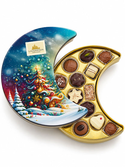 Pralinen Präsentdose Mond Blau 175g von Lauenstein Confiserie mit fantasievollem Weihnachtsbaum vor verschneiter Winterlandschaft und 14 Pralinensorten mit und ohne Alkohol
