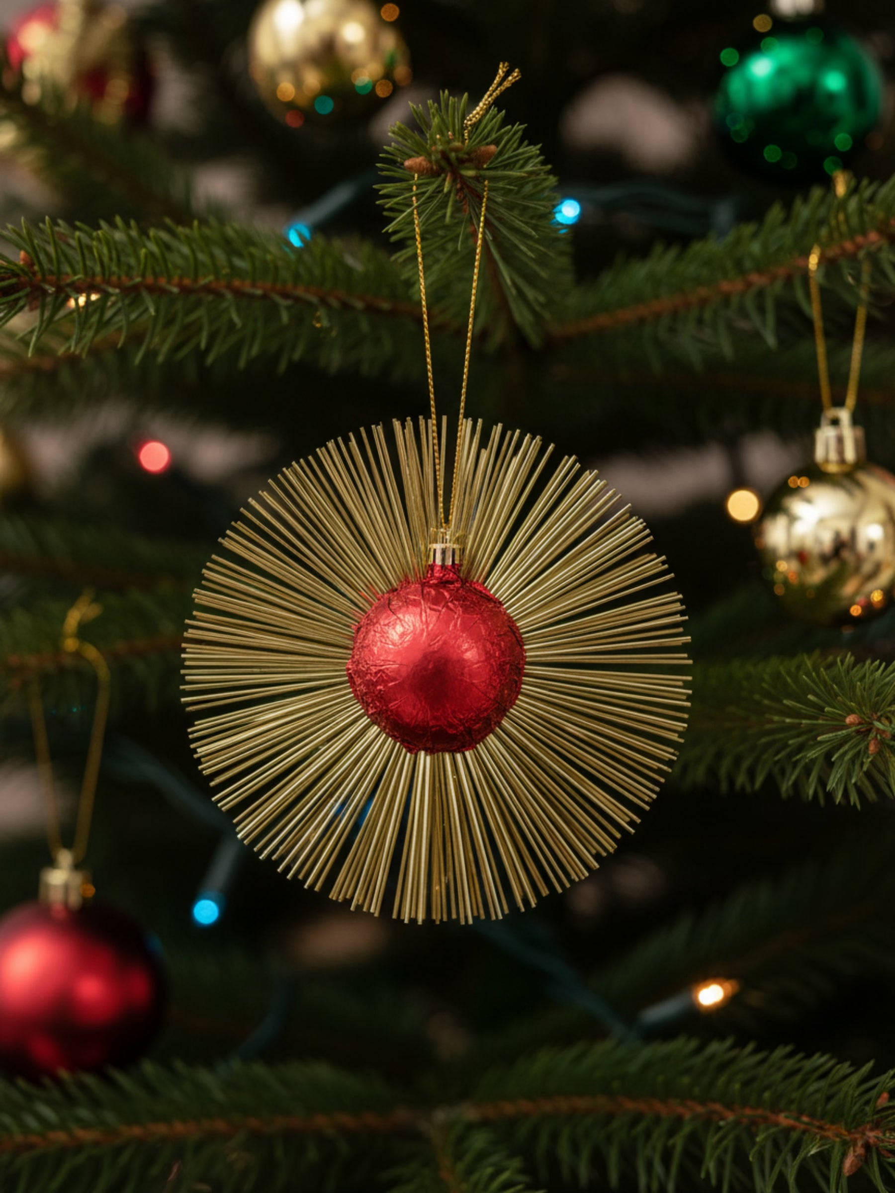 Flimmerstern Rot aus Vollmilchschokolade 10g mit goldenem Lametta und Aufhänger, essbarer Christbaumschmuck, erhältlich in der Dreyer Confiserie in Hameln.